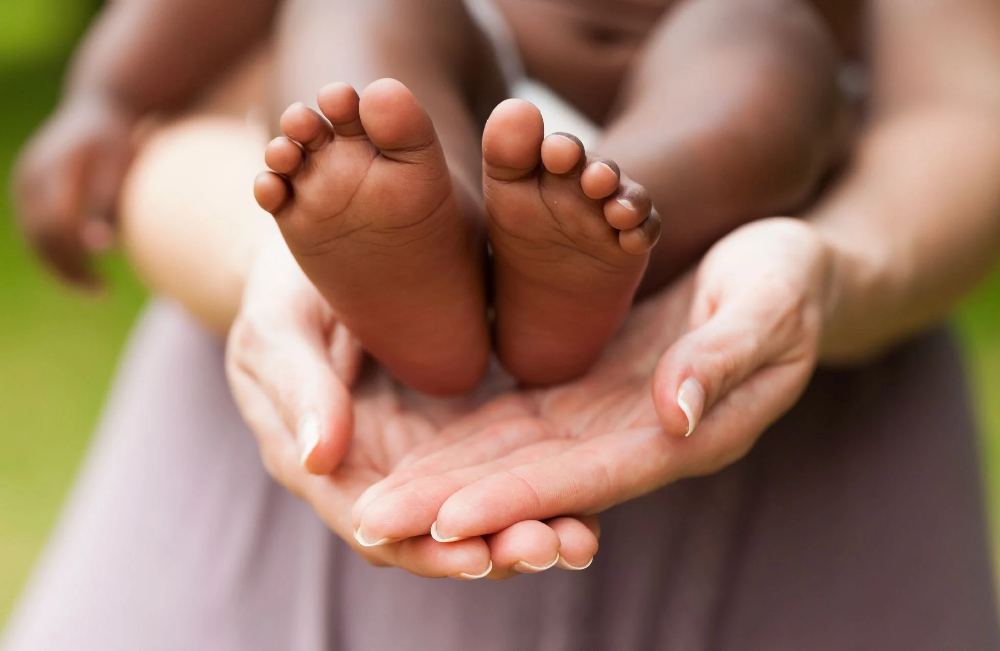 Mains protégeant les pieds d'un bébé